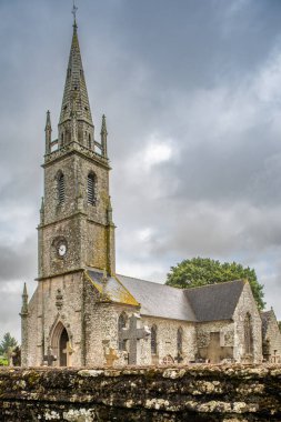 Guehenno, Brittany, Fransa 'da tarihi bir kilise. Yapı, bulutlu bir günde yemyeşil ile çevrili 16. yüzyıldan kalma bir süvariye sahip..