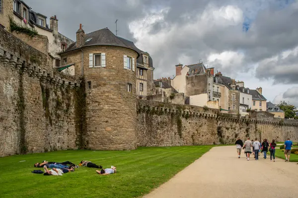 stock image Historic Constable Tower in Vannes, Brittany, France, with people relaxing on the lawn and walking along the pathway on a cloudy day.