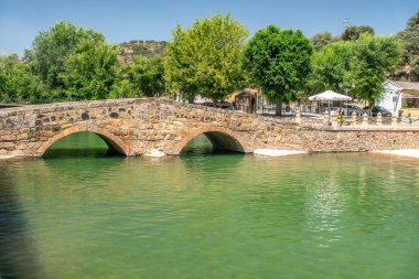 San Nicolas del Puerto, Sevilla, İspanya 'daki Galindon Nehri' nden geçen Roma köprüsü. Yeşillik ve tarihi mimariyle resim gibi bir manzara..