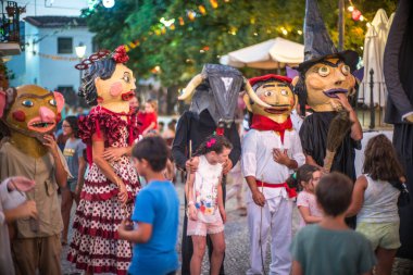 Gigantes y cabezudos at the Fuenteheridos festival in Huelva, Andalucia, Spain with children enjoying the festivities. clipart