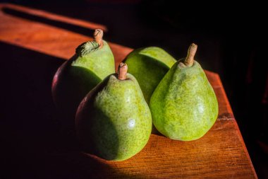 Close up of fresh green pears on a wooden table in Fuenteheridos, Huelva, Andalusia, Spain. Rustic and natural setting. clipart