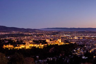 San Miguel Alto 'dan Alhambra ve Granada şehirlerinin çarpıcı alacakaranlık manzarası. Endülüs, İspanya 'da güzel bir mimari ve kültürel dönüm noktası.