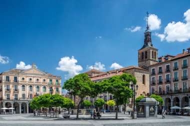 İspanya 'nın Castilla y Leon kentindeki Plaza Mayor' da Juan Bravo Tiyatrosu ve San Miguel Kilisesi manzarası. Açık mavi gökyüzünün altında güzel mimari simgeler.