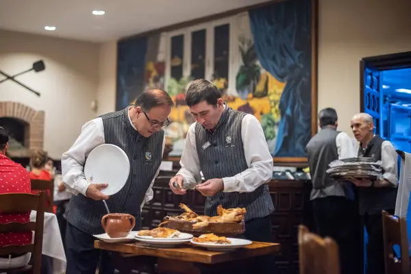 stock image Waiters serving roast suckling pig at the renowned Jose Maria restaurant in Segovia, Castilla y Leon, Spain. A vibrant and traditional dining experience.