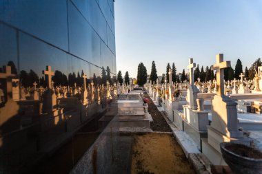 Sevilla, Endülüs 'teki Cementerio de San Fernando' nun günbatımı manzarası. Mezar taşları ve haçlar huzurlu ve yansıtıcı bir atmosfer yaratıyor..