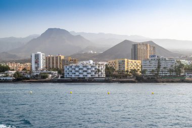 İspanya, Tenerife 'de dağları, binaları ve denizi olan Los Cristianos' un güzel kıyı manzarası. Denizden yakalandılar..