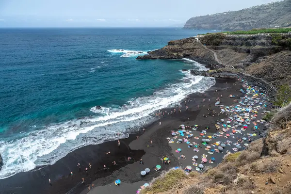 stock image A scenic view of Playa del Bollullo on the north coast of Tenerife in La Orotava, showcasing black sand, blue ocean, and beachgoers.