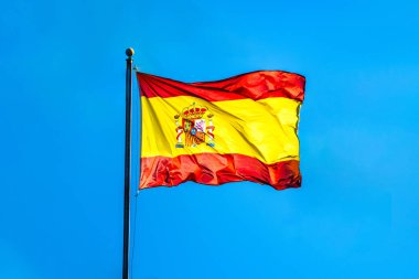 İspanya bayrağı, Sevilla 'da açık mavi gökyüzüne karşı sallanarak ulusal gurur ve coşkulu bir kültür hissi uyandırıyor..