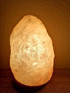 Tahta bir duvarın önünde parlayan Himalaya tuz lambası