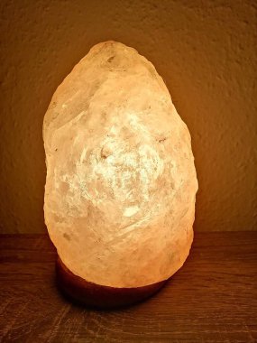 Tahta bir duvarın önünde parlayan Himalaya tuz lambası