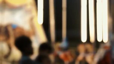 Eğlence parkında dönen, aydınlatılmış, odağını kaybetmiş, altın rengi bir atlıkarınca. Bulanık parlak atlı karınca geceleri parlıyor ve dönüyor. Çocukluğun parlak dönen sembolü. Eğlence fuarı atmosferi.