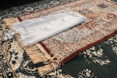 Yeşil halıda beyaz bir türban ve kahverengi desenli bir seccade. Cemaat duasının imamının hasırı. Müslüman duası.