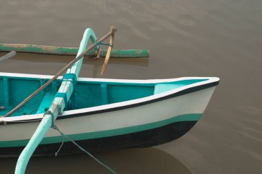 A small traditional wooden boat is idling at the confluence of river and sea water between mangrove forests. clipart