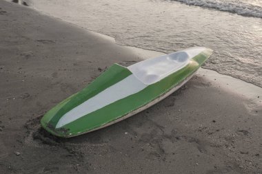 Kano teknesi sahilde ve denizde. Kumsalda yeşil ve beyaz kano teknesi.