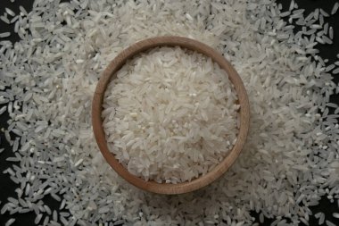 Tahta kasede çiğ beyaz pirinç ya da pirinç zeminli ahşap tabak. Çiftçiler tarafından toplanan saf beyaz pirinç taneleri..