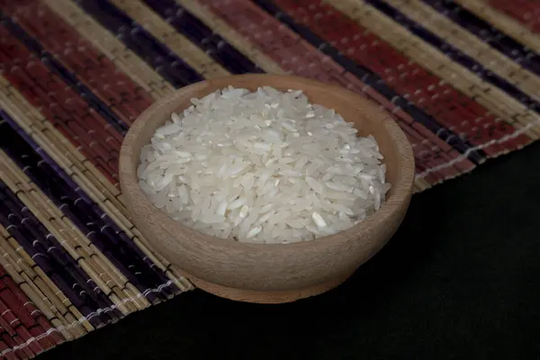 Tahta kasede çiğ pirinç ve beyaz arka planda izole edilmiş ahşap hasırın üzerine saçılmış pirinç yığını. Bir grup saf çiğ pirinç çiftçiler tarafından toplandı. Ahşap tabakta pirinç modern konsept fotoğrafçılık.