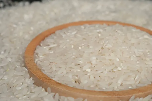 Tahta kasede çiğ beyaz pirinç ya da pirinç zeminli ahşap tabak. Çiftçiler tarafından toplanan saf beyaz pirinç taneleri..