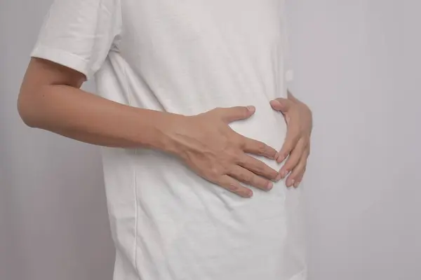 Adamın mide ağrısı ve mide iltihabı vardı. Elini karnına koydu ve rahatlamak için sıktı. Rahatlaması için tuvalete gitmesi gerekiyor. Kaka yapması lazım..