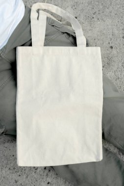 Düz beyaz tişört giyen, elinde temiz beyaz bir çanta tutan genç bir adam. Temiz taşıma çantası modeli konsepti.