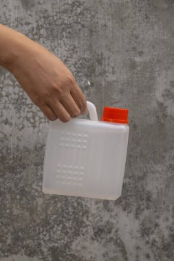 Bir kadının eli, izole edilmiş bir arka planda çeşitli sıvıları taşımak için küçük bir bidon tutuyor..