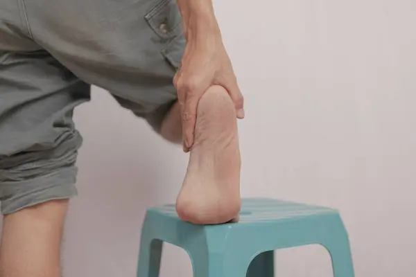 El ile tutulan bilek iltihabı. Acı genç bir adamın ayak bileğine saldırır. Bacak kemikleri üzerinde sağlık kavramı. Ağrıyan bacağını tutan ayak bileği ağrısı. Vücut ağrısı kavramı..