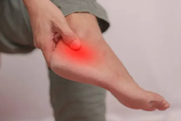 El ile tutulan bilek iltihabı. Acı genç bir adamın ayak bileğine saldırır. Bacak kemikleri üzerinde sağlık kavramı. Ağrıyan bacağını tutan ayak bileği ağrısı. Vücut ağrısı kavramı..