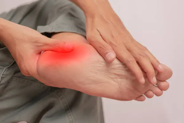 El ile tutulan bilek iltihabı. Acı genç bir adamın ayak bileğine saldırır. Bacak kemikleri üzerinde sağlık kavramı. Ağrıyan bacağını tutan ayak bileği ağrısı. Vücut ağrısı kavramı..