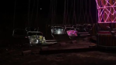 Eğlence salıncağı, atlıkarınca zinciri boş sandalyeler, hiç kimse binmeden, gece karnaval lunaparkında sallanan atlı karınca..