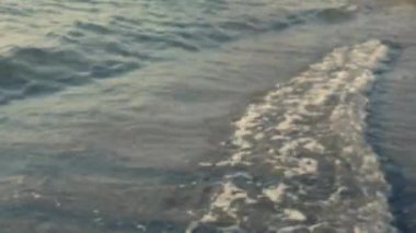 Defocus köpüklü deniz suyu, kumsalda doğal gün batımı ışınlarıyla el sallayarak sıcak okyanus dalgalarının ve okyanus manzarasının tadını çıkarır..