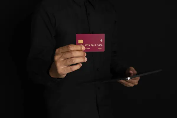 Siyah arka planda el ele tutuşan kredi kartı. Çevrimiçi yeni aktarımı kavra.