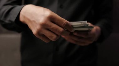 Birinin elinde dolar banknotları. Zengin bir Asyalı para sayıyor, elleri yakın. İş ve finans kavramı. Asyalı adam Amerikan doları yığınını fırlatıyor..