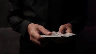 Birinin elinde dolar banknotları. Asyalı bir adam para sayar, elleri yakındır. İş ve finans kavramı. Asyalı adamın elleri Amerikan dolarlarını sayıyor. Adamın eli para tutuyor..