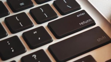 Modern dizüstü bilgisayarın klavyesindeki enter tuşuna yakın çekim. Adam dizüstü bilgisayardaki enter tuşuna basar. 