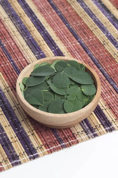 Moringa yaprakları (Moringa Oleifera) beyaz arka planda gerçek taze moringa yaprakları ile ahşap kasede bulunur. Sağlıklı ürünler, süper yiyecekler, vitaminler.
