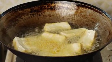 Kavurma yağıyla dolu bir tavada soya peyniri kızartma videosu..