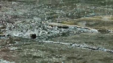 Yere şiddetli yağmur damlaları yağıyor. Yağmurlu bir günde beton zemine yağmur damlaları düşer. Beton zemine yağmur damlaları.