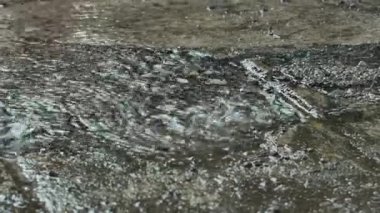 Yere şiddetli yağmur damlaları yağıyor. Yağmurlu bir günde beton zemine yağmur damlaları düşer. Beton zemine yağmur damlaları.