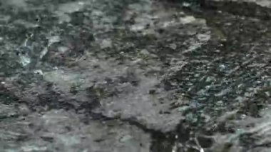 Yere şiddetli yağmur damlaları yağıyor. Yağmurlu bir günde beton zemine yağmur damlaları düşer. Beton zemine yağmur damlaları.