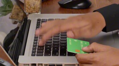 Gençlerin eli kredi kartıyla internetten alışveriş yapıyor. Adam bilgisayarı kullanıyor ve evde online işlem yapıyor. Teknoloji ve yaşam tarzına göre online alışveriş kavramı.