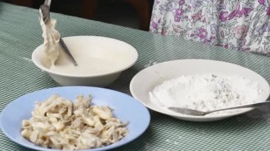 Baharatlı un içinde istiridye mantarı yapıp sonra da onları kızgın yağda kızartan genç bir kadın..