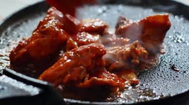 Gaz ocağında ızgara tavada ızgara kırmızı baharatlı tavuk. Sarı zerdeçal baharatlı çiğ tavuk eti, sarımsak ve ızgarada yeşillik pişiriyorum. Kızarmış tavuk dilimi..