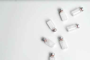 Beyaz arka planda metin boşluğu olan aşı şişelerinin düz hali. Aşı tüplerinin bembeyaz arka planı, sağlık tıbbi konsepti.