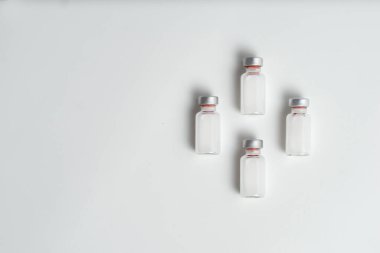 Beyaz arka planda metin boşluğu olan aşı şişelerinin düz hali. Aşı tüplerinin bembeyaz arka planı, sağlık tıbbi konsepti.