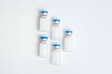 Beyaz arka planda metin boşluğu olan aşı şişelerinin düz hali. Aşı tüplerinin bembeyaz arka planı, sağlık tıbbi konsepti.