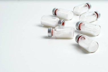 Beyaz arka planda metin boşluğu olan aşı şişelerinin düz hali. Aşı tüplerinin bembeyaz arka planı, sağlık tıbbi konsepti.