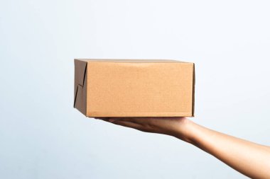 Kadın beyaz arka planda kahverengi bükülmüş kutuyu tutuyor. Beyaz izole edilmiş arka planda küçük kahverengi dikdörtgen kutu tutan genç bir kadın..