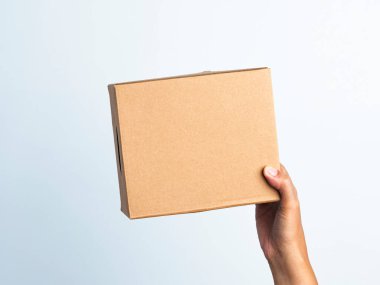 Kadın beyaz arka planda kahverengi bükülmüş kutuyu tutuyor. Beyaz izole edilmiş arka planda küçük kahverengi dikdörtgen kutu tutan genç bir kadın..