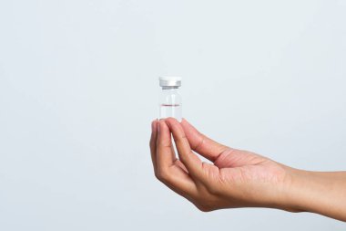 Beyaz arka planda aşı için hazırlanmış bir hemşire eli. Bakıcının elinde, içinde kornea filmi bulunan bir şişe var..