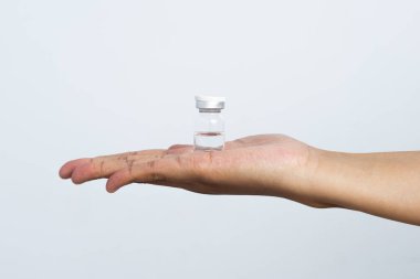 Beyaz arka planda aşı için hazırlanmış bir hemşire eli. Bakıcının elinde, içinde kornea filmi bulunan bir şişe var..