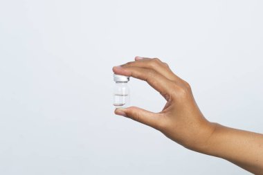 Beyaz arka planda aşı için hazırlanmış bir hemşire eli. Bakıcının elinde, içinde kornea filmi bulunan bir şişe var..